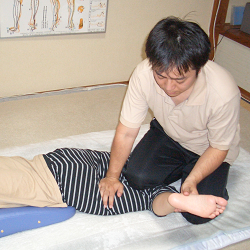 新潟市ぜん整体院の心系を膝で圧している写真。ガニ股に対する施術。